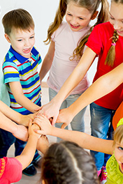 Starke Kinder halten die Hände in die Mitte und zeigen Teamgeist.